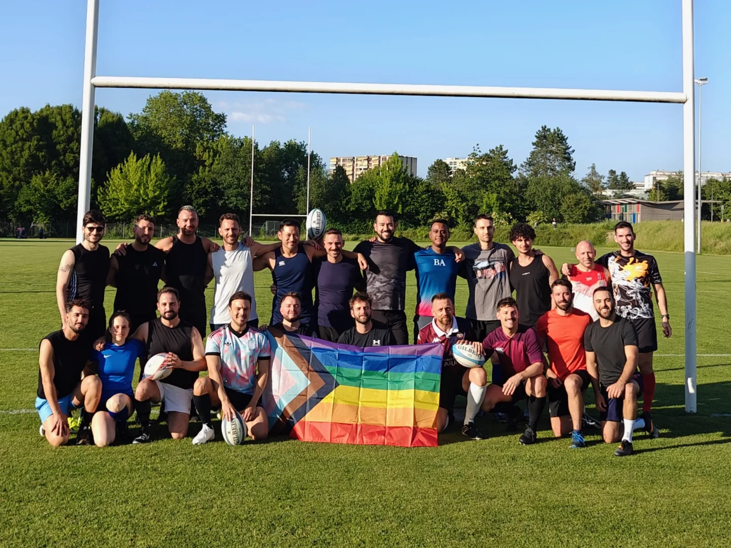 Guardians beneath the rugby posts with rugby balls and a Pride flag